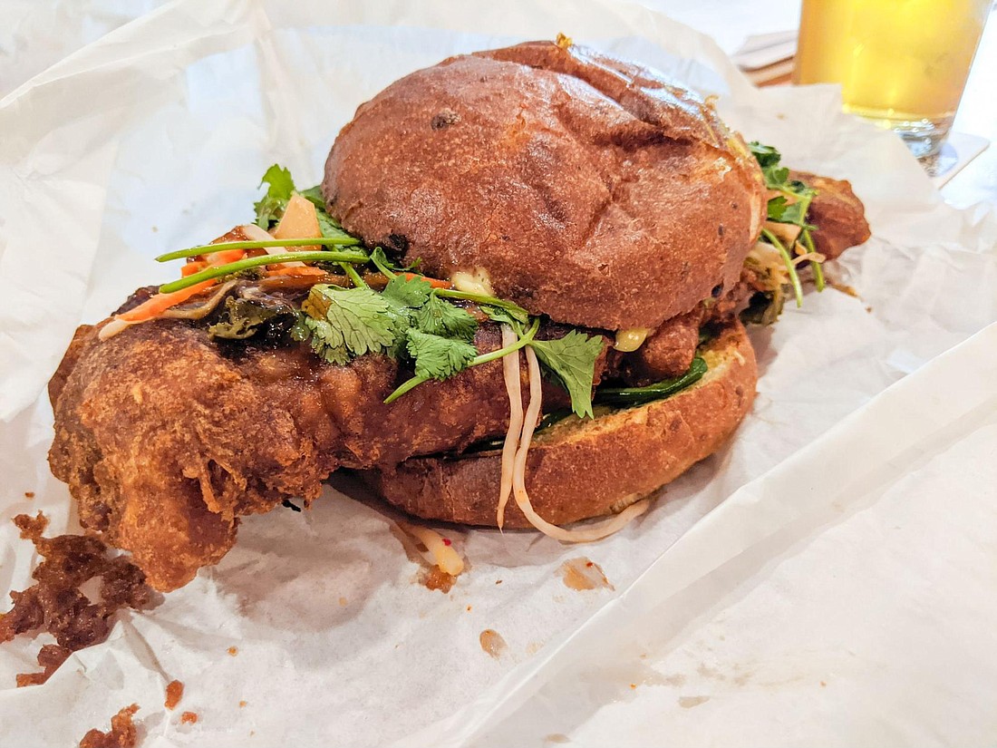 The Korean chicken sandwich can barely be contained by its bun.
