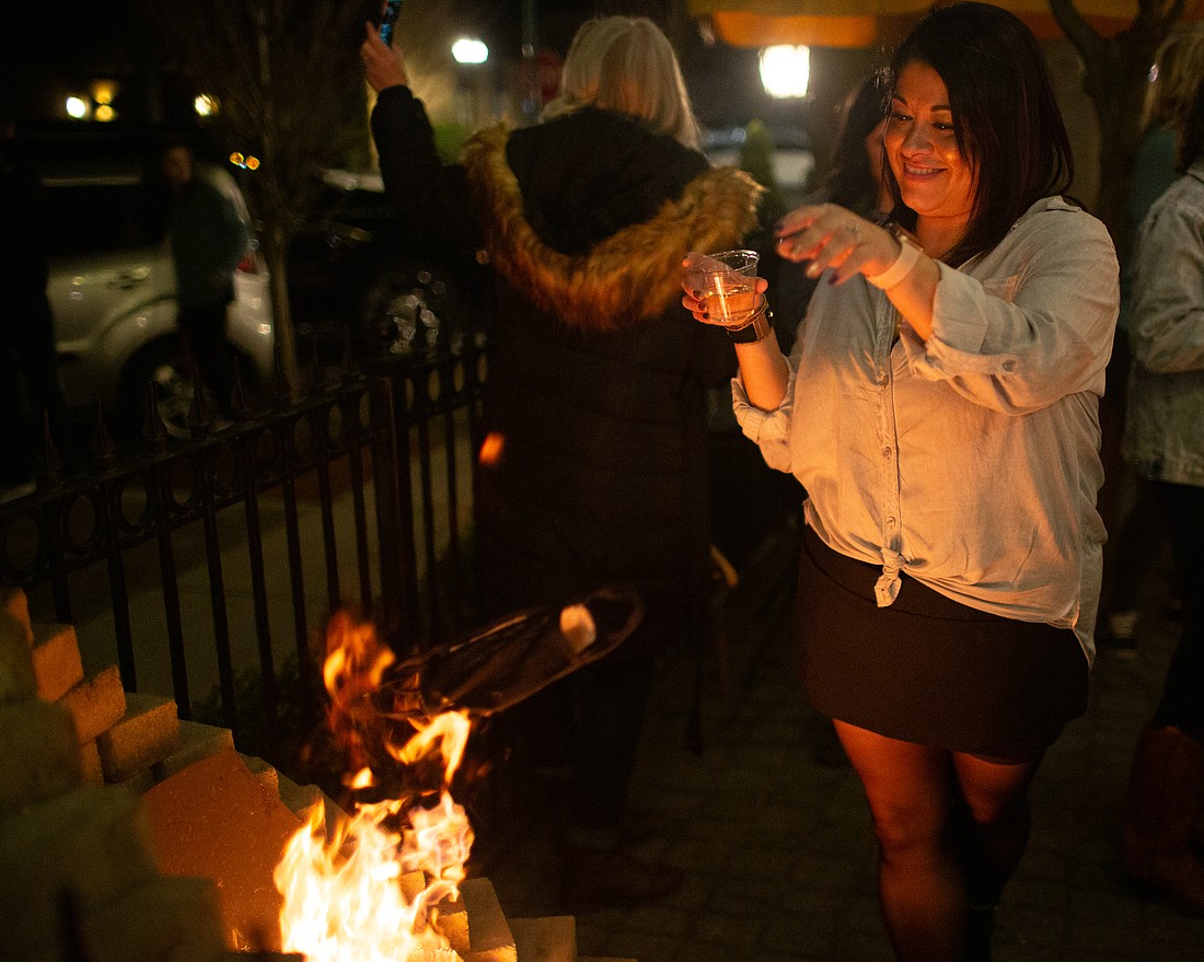 The Mill at Seventh owner Linda Wohlrab drops her mask into the fire on March 11.