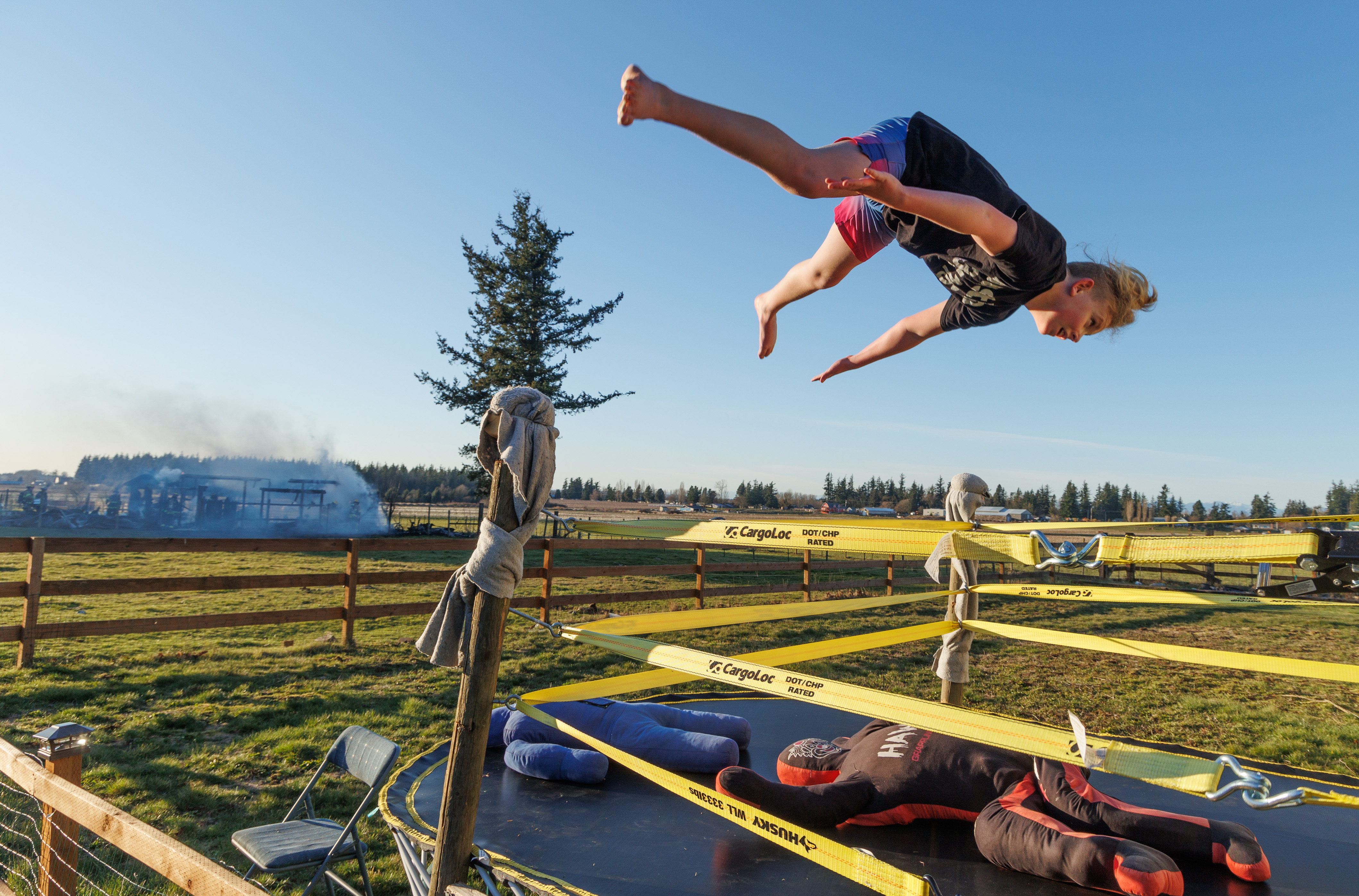 Rubin Hutchins performs a Swanton Bomb wrestling move as firefighters put out a shed fire in the background along West Bartlett Road in Lynden on March 9.