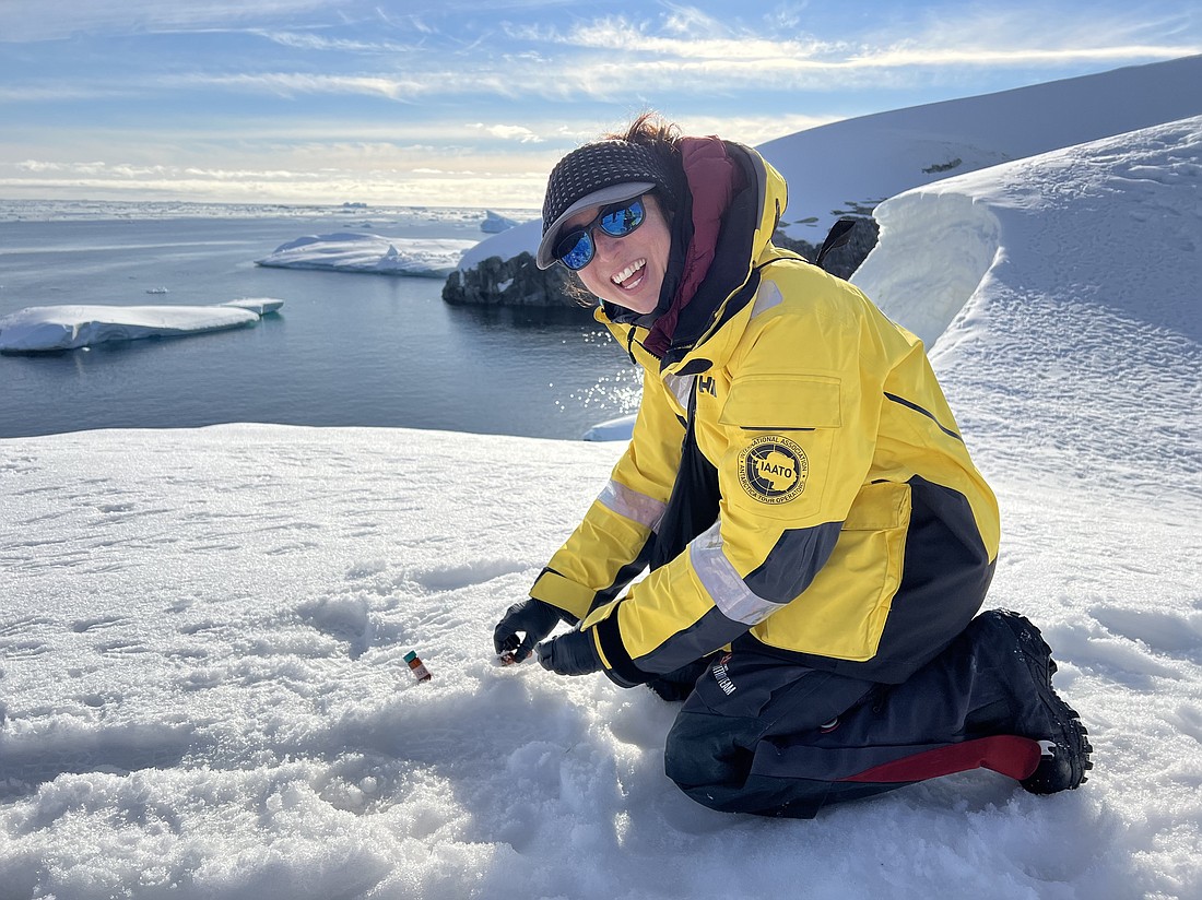 Alia Khan kneels in the Antarctic snow to collect samples for later analysis.