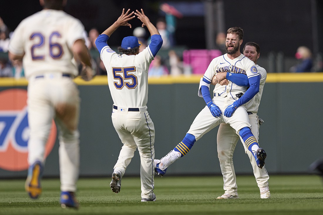 Seattle Mariners’ Jesse Winker, front right, is lifted by Ty France as he celebrates a win over Kansas City Royals in 12 innings of a baseball game, Sunday, April 24, 2022, in Seattle.