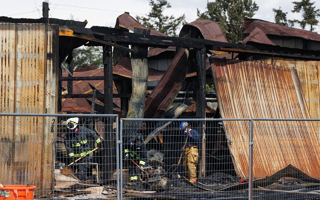 Fire investigation personnel sift through the wreckage of a warehouse on Lummi View Drive on May 11. The warehouse was destroyed in a fire the previous night.