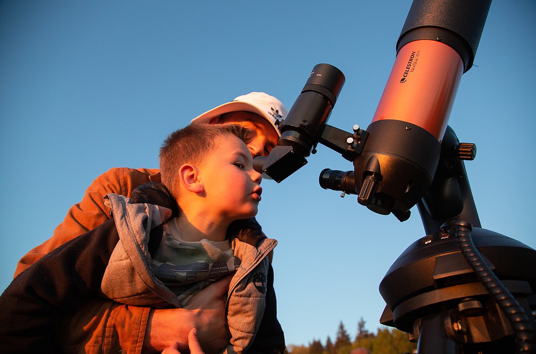 Cooper Clark lifts his son Tyson, 5, up to look at the half moon through the telescope at Boulevard Park on May 8. Every half moon, the Whatcom Association of Celestial Observers sets up their telescopes at the popular park to give the community the opportunity to see the moon up close.