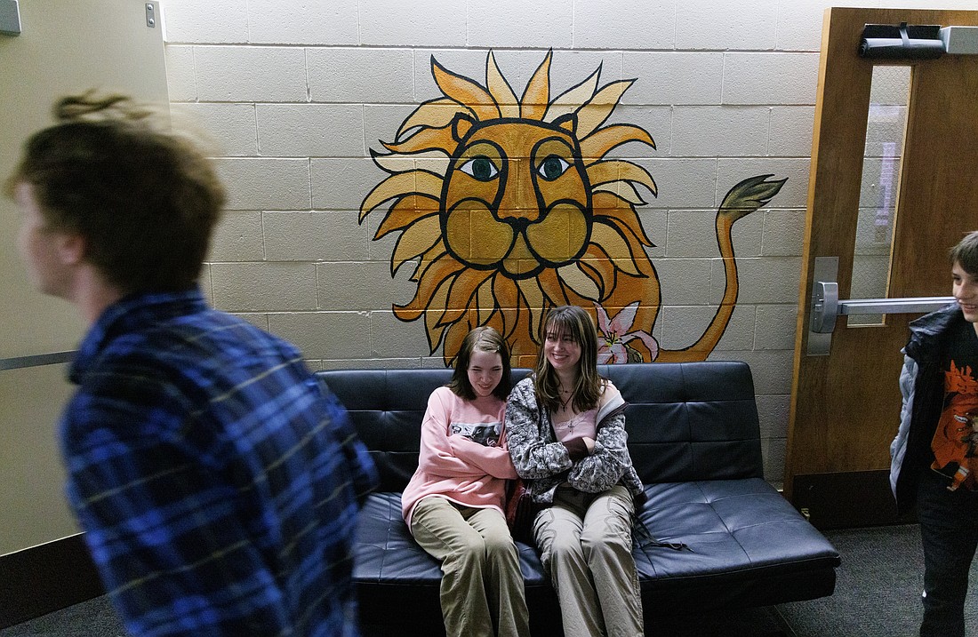 Former Sunnyland Elementary students Ryn Clark and Lolo Goodenough sit on a bench below a lion during an open house tour of the school on June 9. The School will be torn down this summer to make room for the new school, currently under construction.