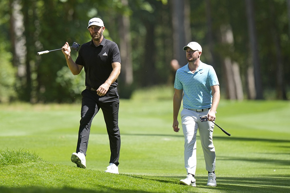 Dustin Johnson of the United States, left, and Sam Horsfield of Britain walk on the course during the final round of the inaugural LIV Golf Invitational at the Centurion Club in St. Albans, England, June 11.