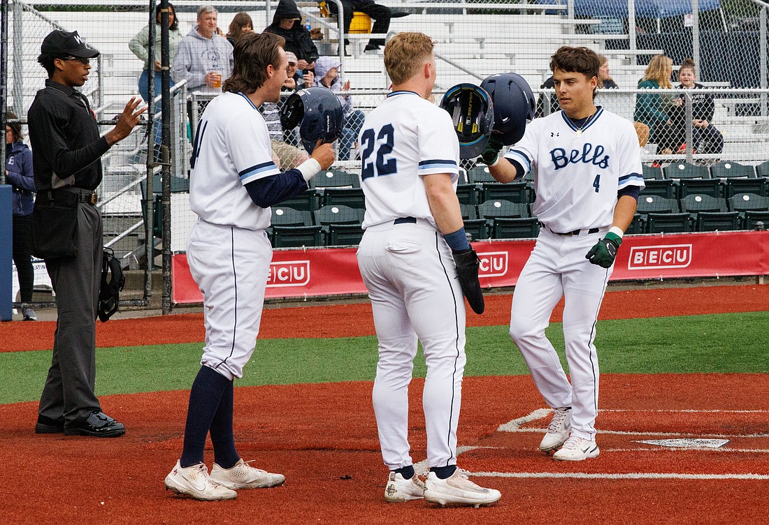 Crossing home plate, Bellingham's Gavin Schulz (4) taps his helmet with teammates Willis Cresswell and Daniel Gernon after hitting a three-run homer as the Bells beat the Wenatchee AppleSox 4-1 at Joe Martin Field on June 15.
