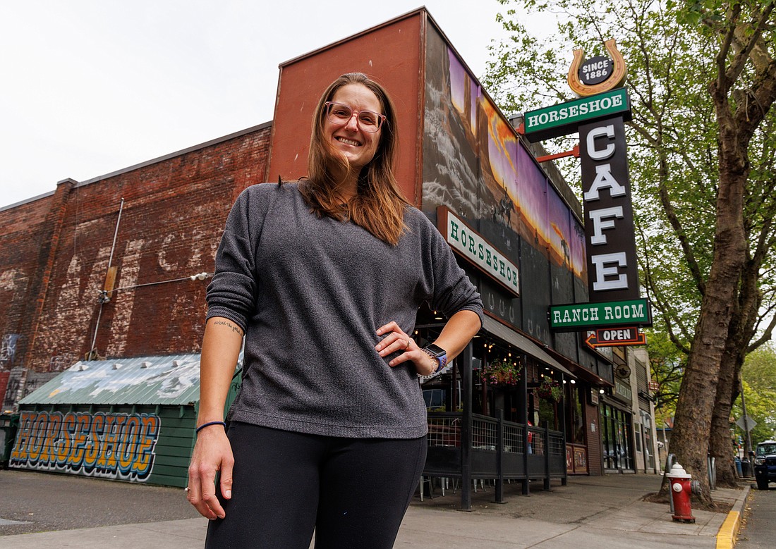 Horseshoe Café co-owner Kate Groen stands near the restaurant's new sign, June 17 on Holly Street in Bellingham. Groen said she wanted the new sign to evoke the 1950s version it replaced, only with a reversed horseshoe.
