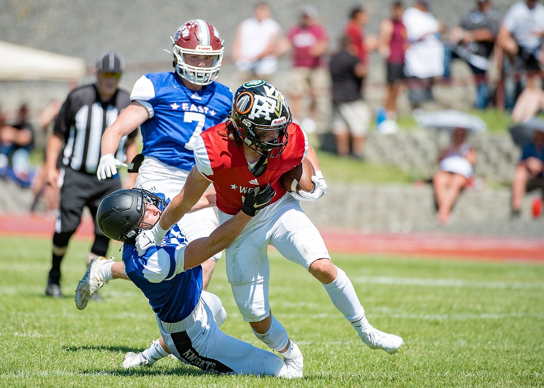 Blaine's Jaxon Kortlever stiff arms a defender from the East team at the Earl Barden Classic in Yakima on June 25.
