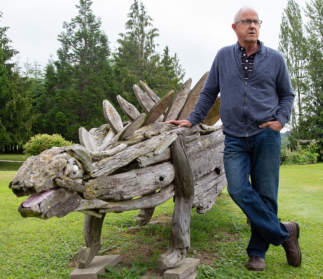 Joe Treat leans against his driftwood stegosaurus sculpture on display outside of his home in Bow on July 1. Other animals at Bowrassic Park include a horse, ostrich, kangaroo, alligator, bulldog and more.