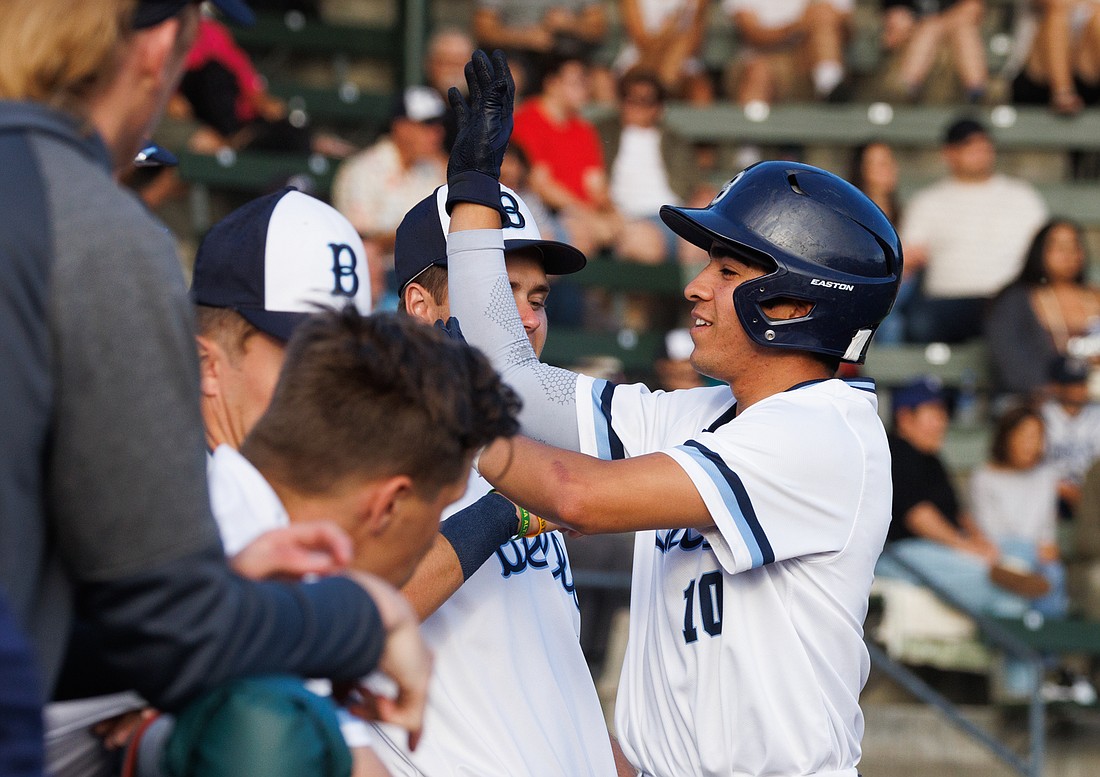 Christopher Campos high-fives teammates after scoring on a walk as the Bellingham Bells tie up the game 1-1 Thursday, July 7.