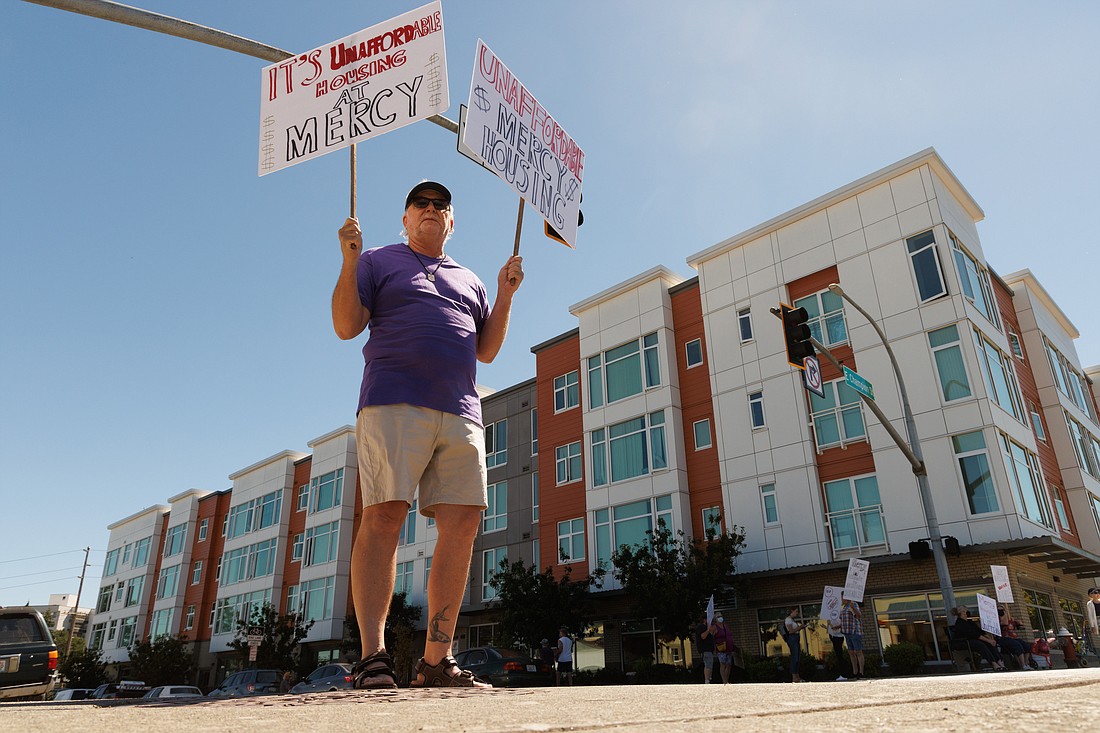 Along with a dozen others, Daniel Rinier, a resident of the Eleanor Apartments, protests on North Forest Street about another rent increase at the affordable housing complex.