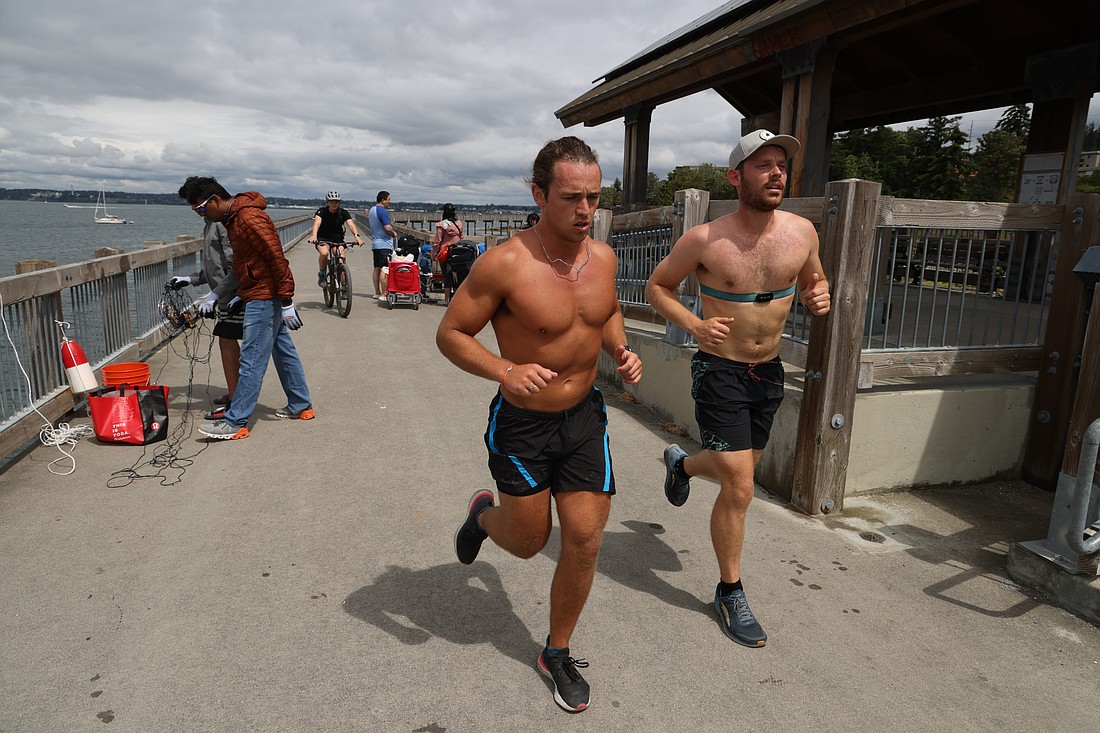 After a 110-mile bike ride, Jake Birnel, left, and Ethan Hunger continue with a 13-mile run along Taylor Dock on July 16. Hunger burned more than 11,000 calories during his 4:30 a.m. to late night ride, bike, swim and high-intensity exercise legs to raise money for the Bellingham Food Bank.