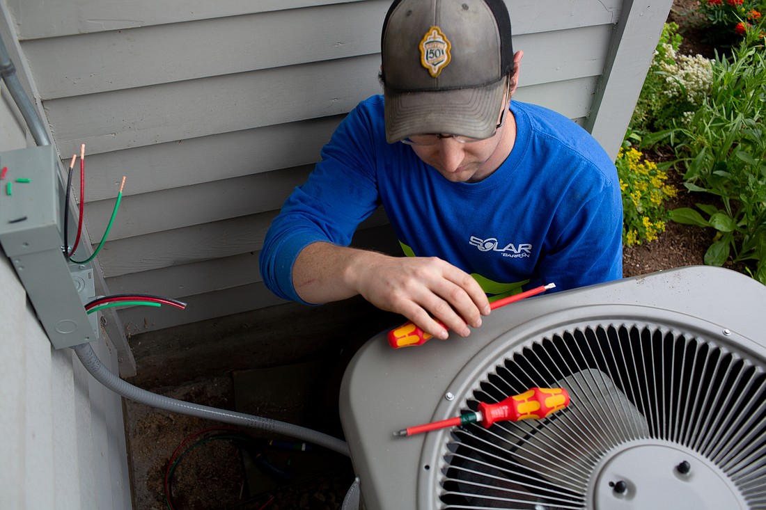 Electrician Brady Irwin installs an air conditioner at a home in Ferndale on July 18. Barron Heating AC Electrical & Plumbing has seen prices of HVAC equipment increase significantly due to inflation over the last 12 months.