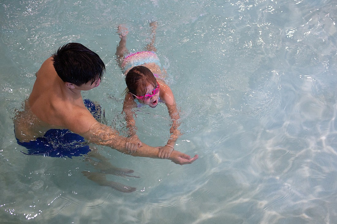 Noah Chen, 15, helps student Ana practice her strokes and breathing while swimming to a wall at Arne Hanna Aquatic Center on July 29. Chen and his brother Nathan, 18, provide free lessons to low-income and foster children.