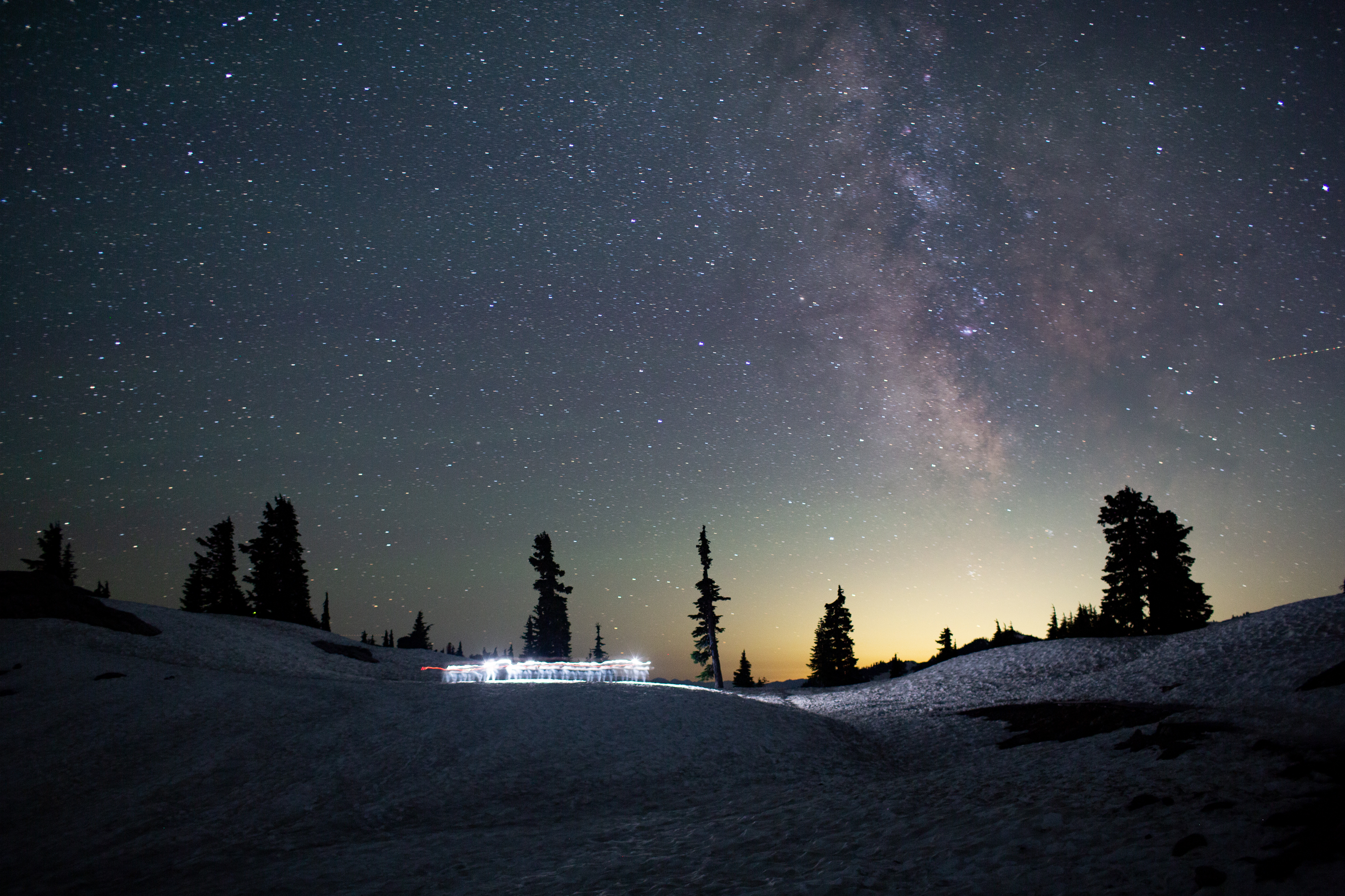 Two people move across a snowfield at Artist Point beneath the Milky Way at 11:55 p.m. on July 30.