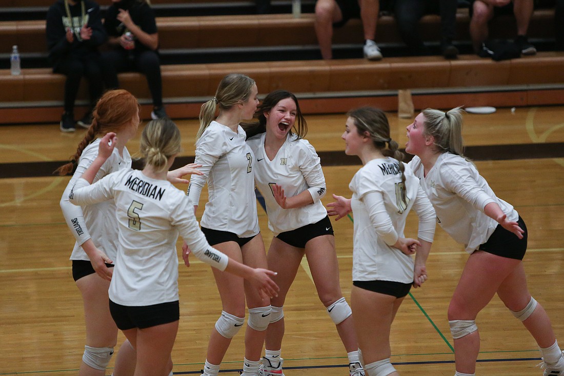 The Meridian volleyball team celebrates a point in their match against Lynden on Oct. 19, 2021. The Trojans placed third at the Class 1A state tournament last season.