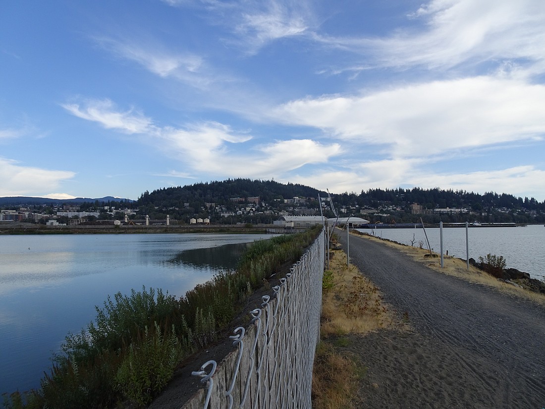 A tall fence separates the ASB Trail from a 28-acre holding pool for polluted water.