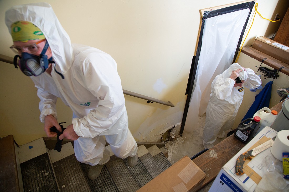 Son Levi Brown, left, and mother Cheryl Brown don hazmat suits and respirators to walk into the basement of their home in Nooksack on Aug. 25. The Browns' home was flooded and filled with naturally occurring asbestos from Sumas Mountain last November.