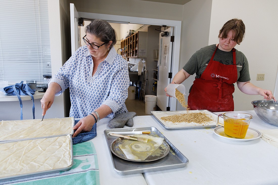 At St. Sophia Greek Orthodox Church, Marie Boulos cuts baklava into servings while Alida Schindler pours nuts over filo dough in preparation for the church's popular Greek Festival, which takes place Sept. 8–11.