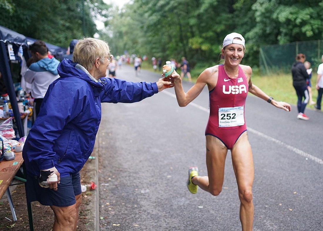 Bellingham's Courtney Olsen grabs a bottle of tea from team lead Lin Gentling while competing for the U.S. women in the International Association of Ultrarunners 100K World Championship in Bernau, Germany on Aug. 27.