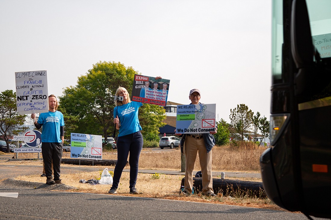 Protesters wave signs at an electric bus as it enters the "Cascadia 2050 Vision: Moving to Climate Action" conference at Semiahmoo Resort on Sept. 12.