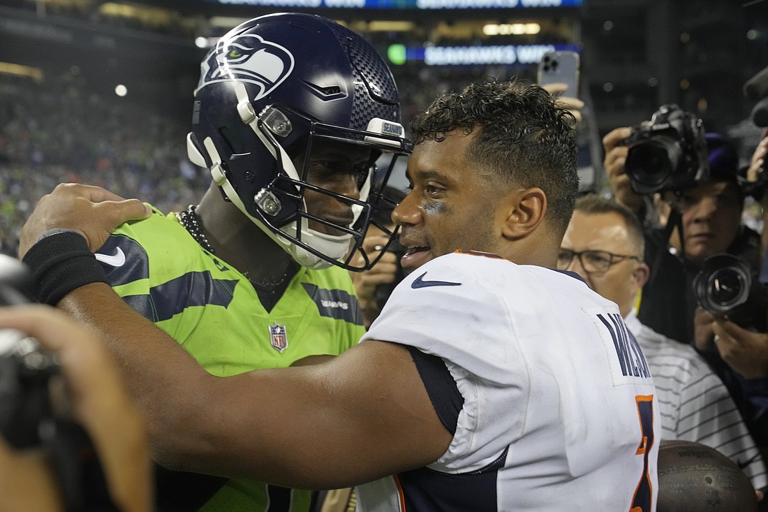 Seattle Seahawks quarterback Geno Smith, left, talks with Denver Broncos quarterback Russell Wilson, right, after an NFL football game, Monday, Sept. 12, in Seattle. The Seahawks won 17-16.