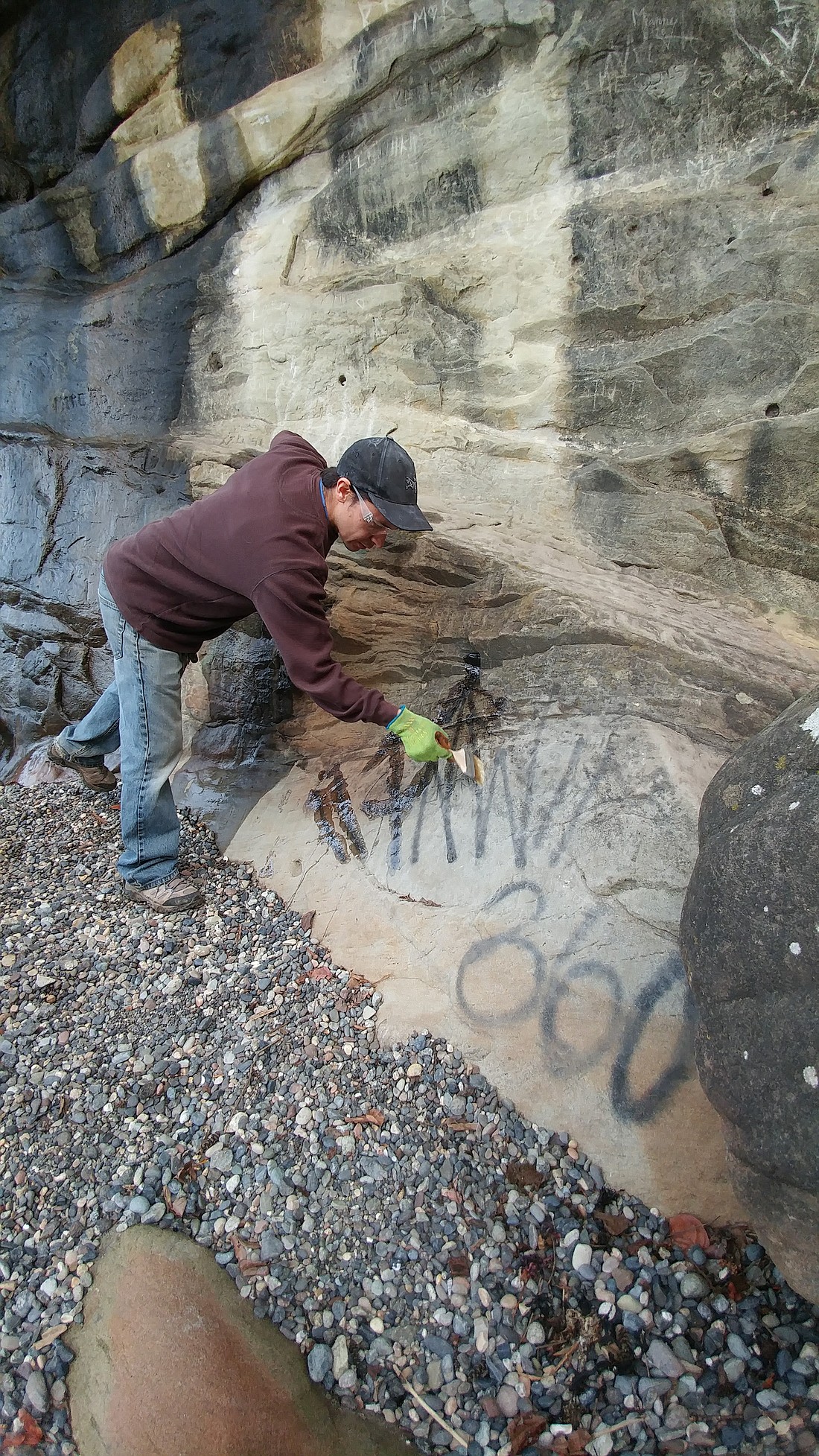 A worker with the Access Fund cleans up graffiti at Larrabee State Park in 2017.