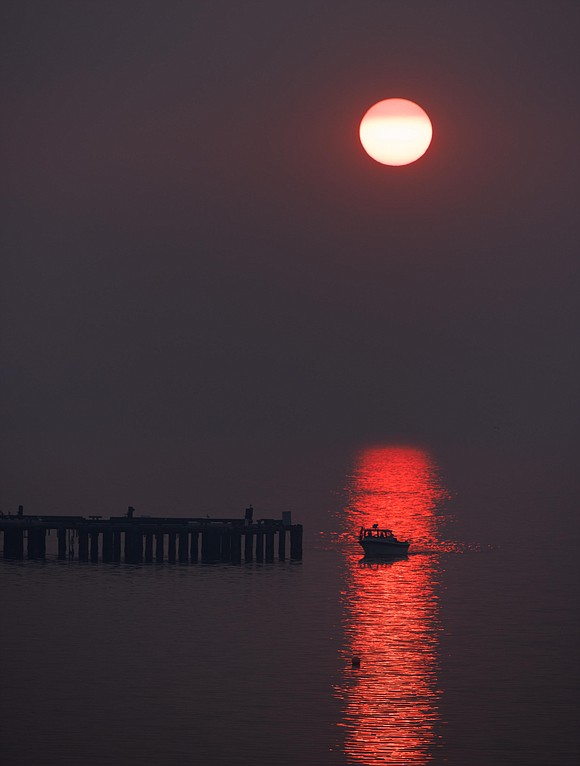 A boat is silhouetted in the sunset reflected off Bellingham Bay due to wildfire smoke on Oct. 18.
