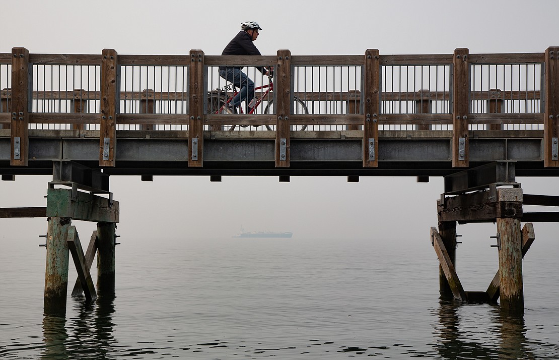 A biker rides along the boardwalk at Boulevard Park as smoke settles, obscuring views of the San Juan Islands, on Oct. 18. Smoke from wildfires in the Cascades brought air quality indexes above 300 in parts of Whatcom County.
