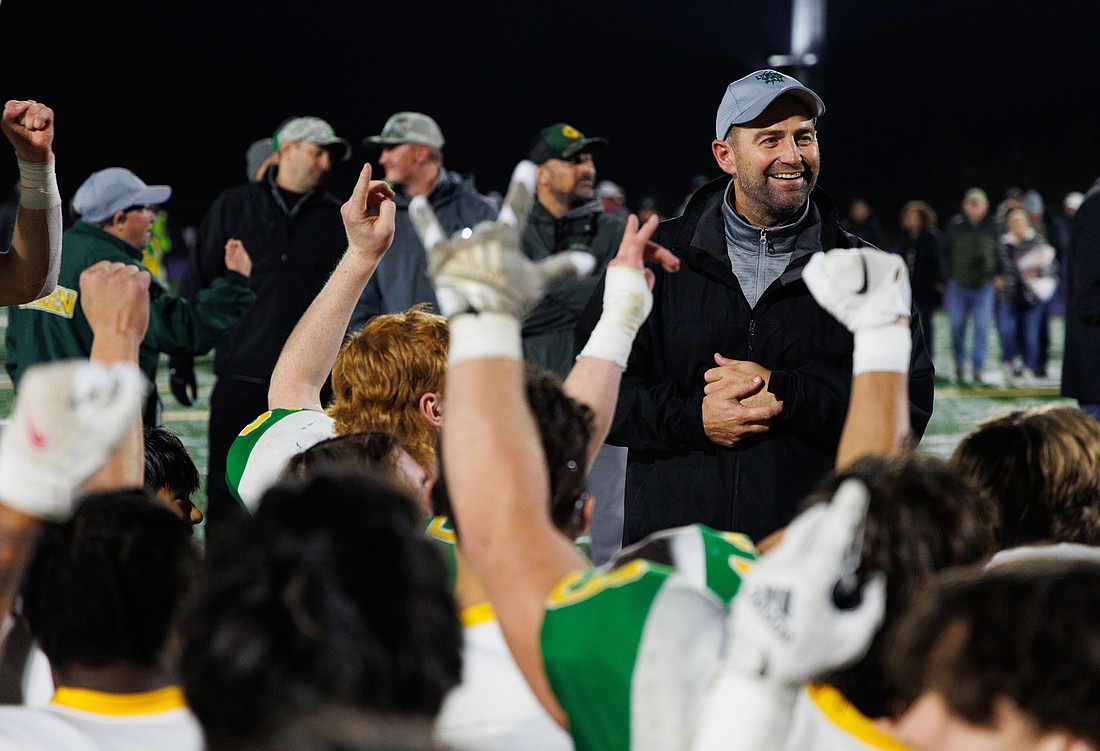 Lynden players cheer on head coach Blake VanDalen after the Lions beat Anacortes to win the league title on Oct. 28.