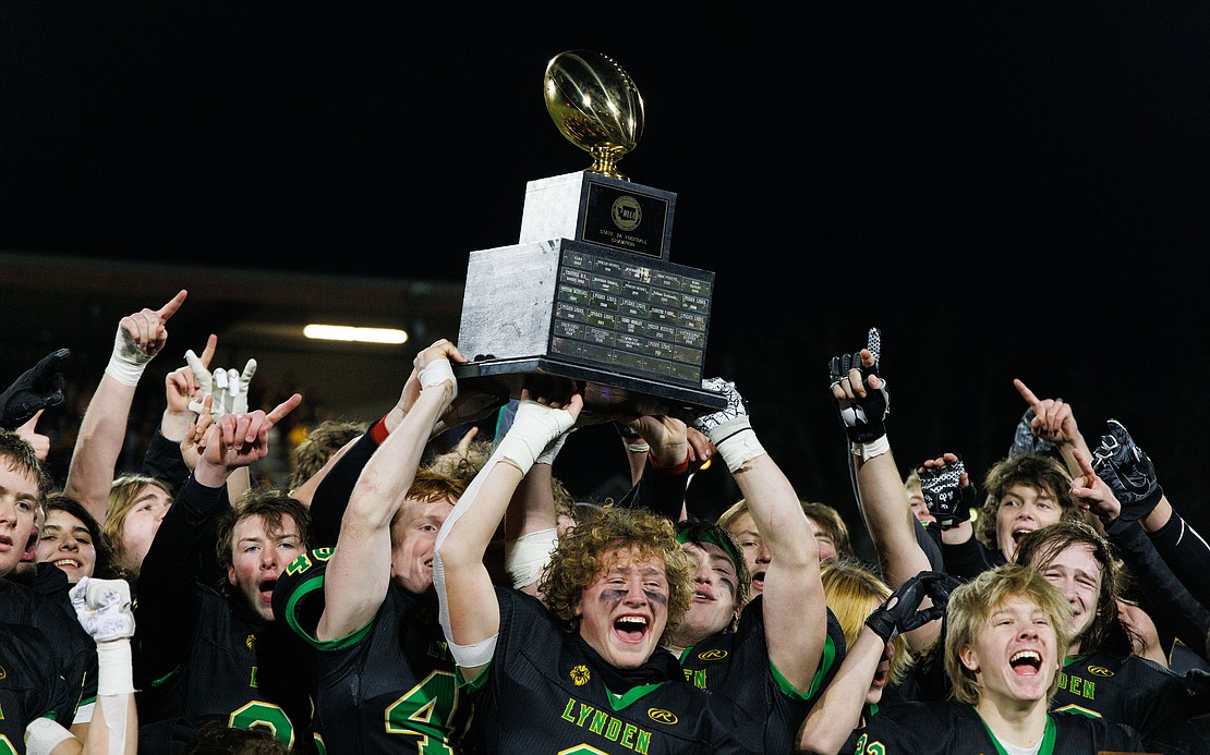 Lynden celebrates with the 2A state championship trophy after the Lions beat North Kitsap 31-24 to win their second-straight title at Sparks Stadium in Puyallup on Dec. 3.