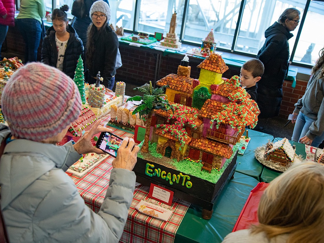 A visitor takes a photo of the "Encanto" gingerbread house built by Michelle Gray at the Port of Bellingham's Gingerbread House Contest in the Bellingham Cruise Terminal on Dec. 4. The house – designed after one in the popular Disney movie – won first place in the Family category.