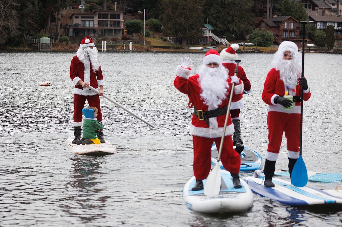 Micah Ping uses a PVC pipe as an oar after forgetting his at home while he and 15 stand-up paddleboarders donned Christmas outfits and paddled around Lake Samish on Dec. 10.