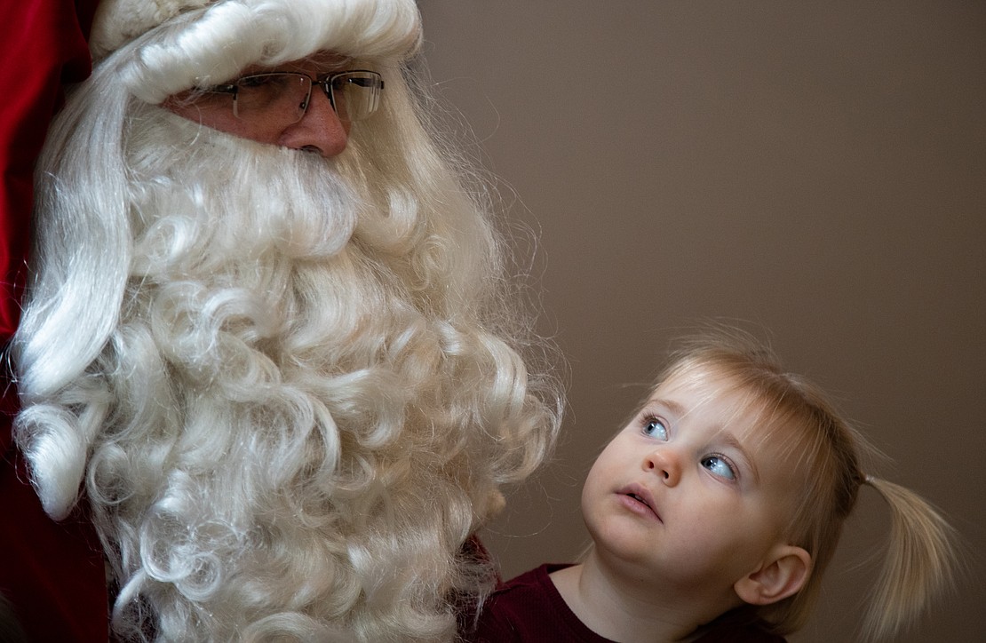 Ellie Brownell, 22 months, inquisitively looks at Santa Claus.
