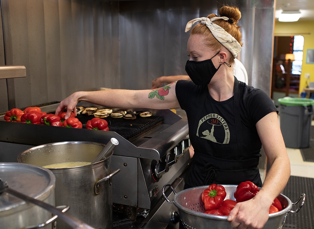 Pepper Sisters co-owner Kelsey Andrews adds red peppers to the grill in July. The three-decade-old downtown restaurant temporarily closed in October with a plan to reopen by year’s end.