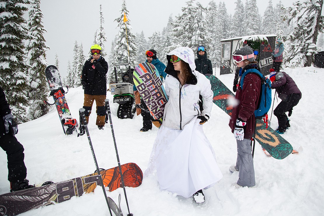 Tara Ortiz grabs her board to hit the slopes with her family in her wedding dress at Mount Baker Ski Area on Feb 14. The ski hill hosted a pop-up wedding chapel for marriages, vow renewals and commitment ceremonies. Ortiz and her husband renewed their vows a decade after they originally married on the mountain.