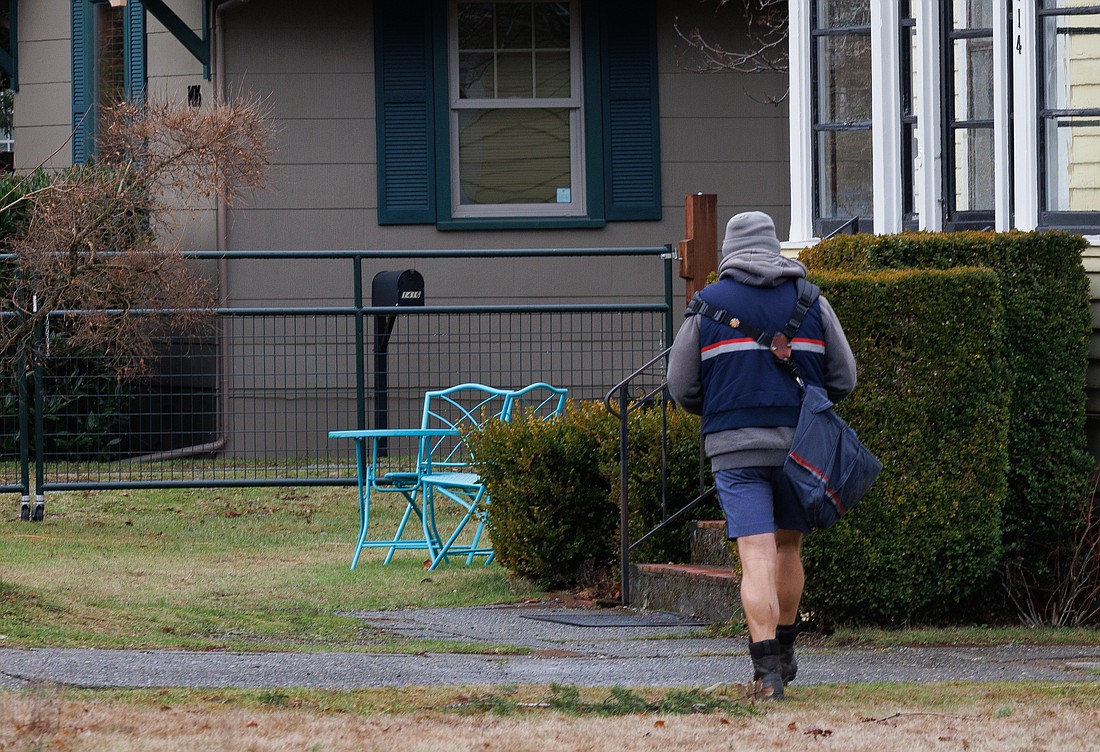 A postal worker walks door-to-door in the Columbia neighborhood delivering mail on Dec. 30, 2022. Homeowners are complaining about delays in the mail service.