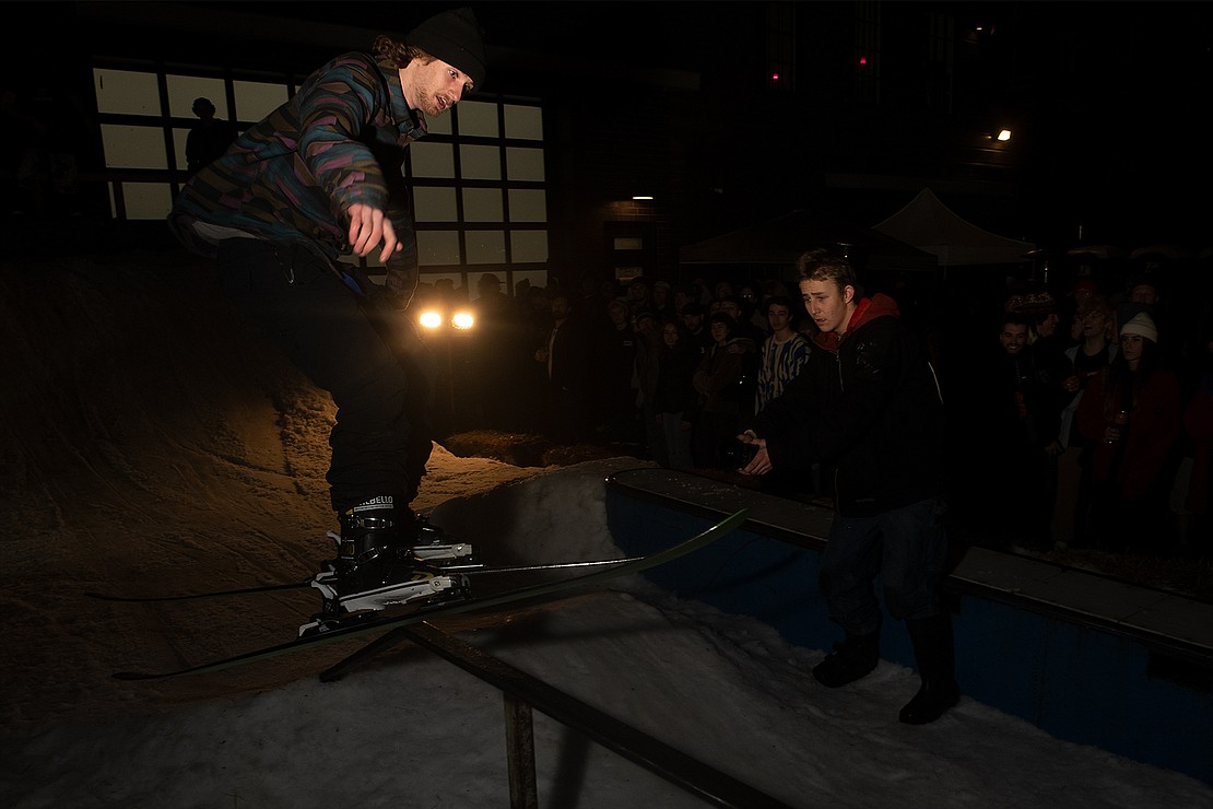 Xander Griffin skis across an up-flat-down rail as Miles Freelan films.