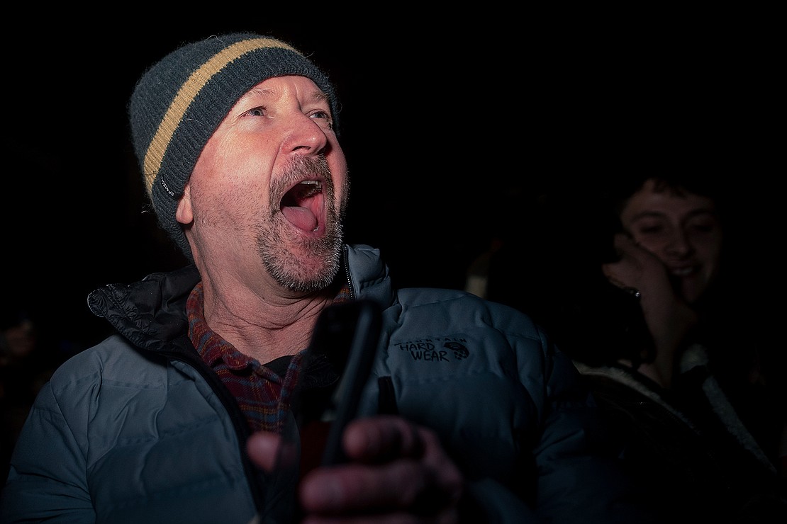 Rodger Pralle reacts to a snowboarder landing a high jump off a steel beam.