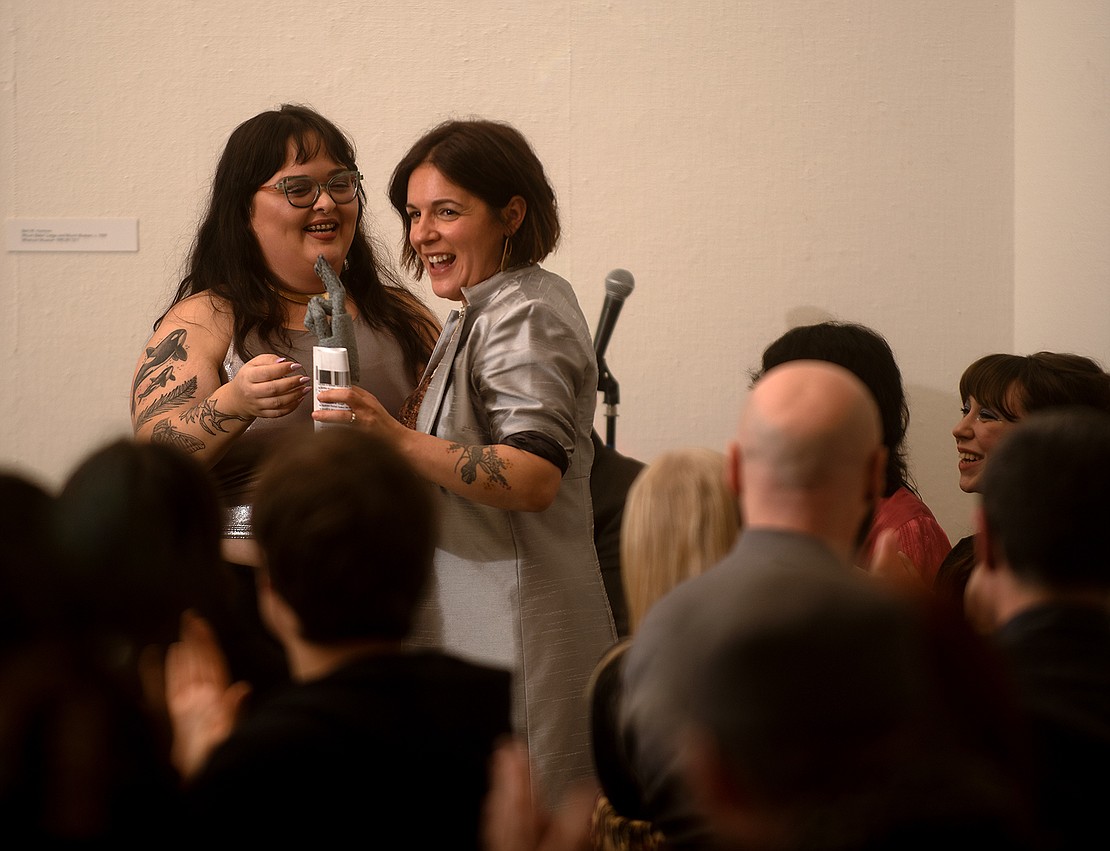 Elizabeth Montoya, left, presents the Champion for All Ages Art and Music Award to Jenn Mason, owner of WinkWink Boutique. "Oh my gosh, this is the coolest award I have gotten," Mason said after receiving the trophy shaped like the sign of the horns hand gesture.