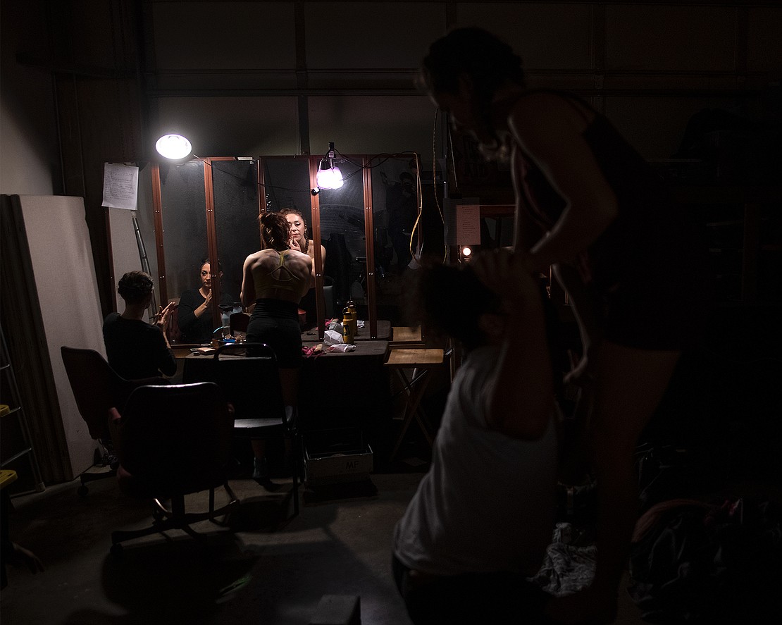Jes Houston, left, and PJ Perry apply makeup and wax while other performers practice backstage.