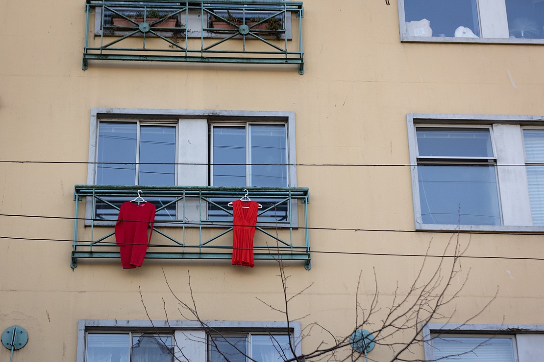 Two red dresses, symbolizing missing and murdered Indigenous women, hang from a window above Alexander Street.