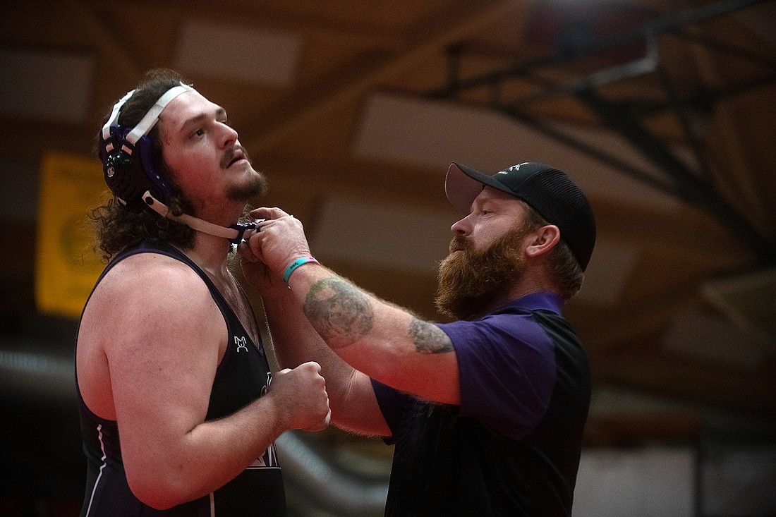Justin Morgan, Nooksack Valley's coach, fixes the headgear of Grayson Coleman at the WIAA 1A Region 1 wrestling tournament on Feb. 11 at Mount Baker High School.