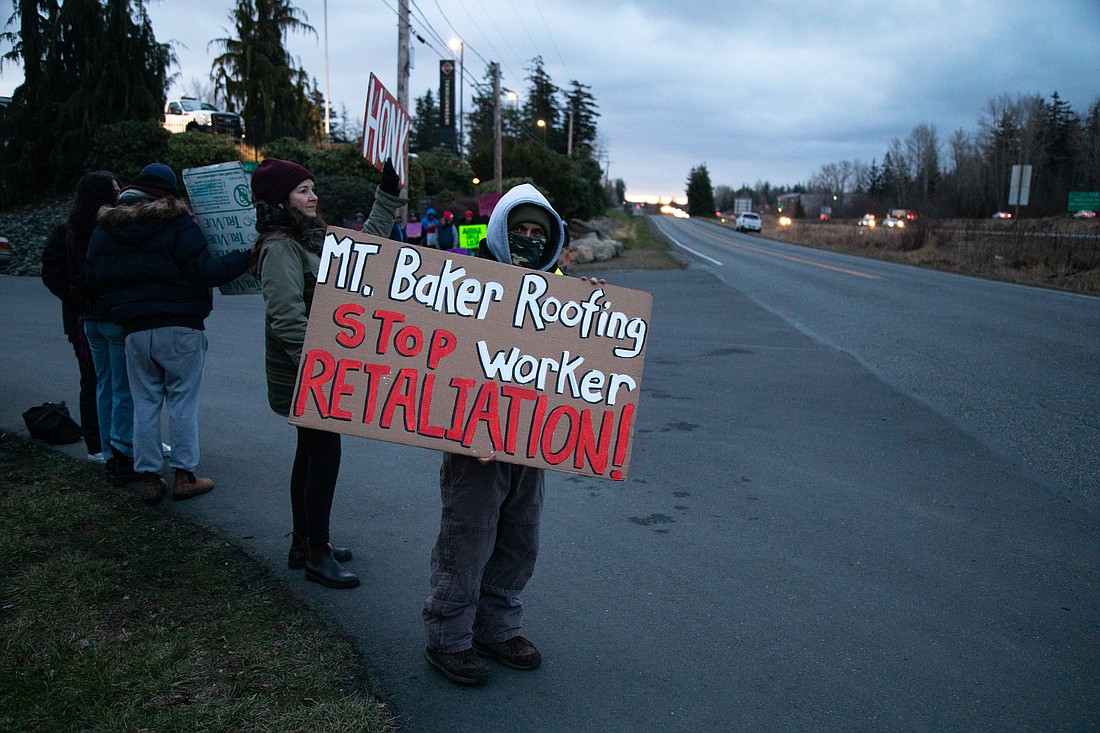 A Mt. Baker Roofing employee holds a sign calling for the end to worker retaliation Feb. 14. A work stoppage occurred following allegations of the company failing to provide bathrooms, water and breaks, and then accusations of the company firing employees for speaking up.