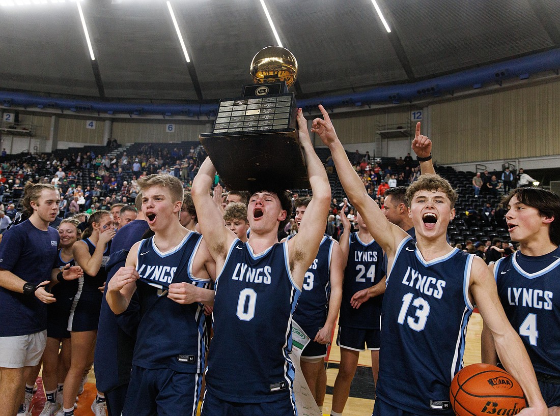 Lynden Christian players celebrate as senior Tyler Sipma (0) holds up the gold ball March 4 after the Lyncs beat King’s 57-47 to secure their second-straight 1A state championship at the Yakima Valley SunDome.