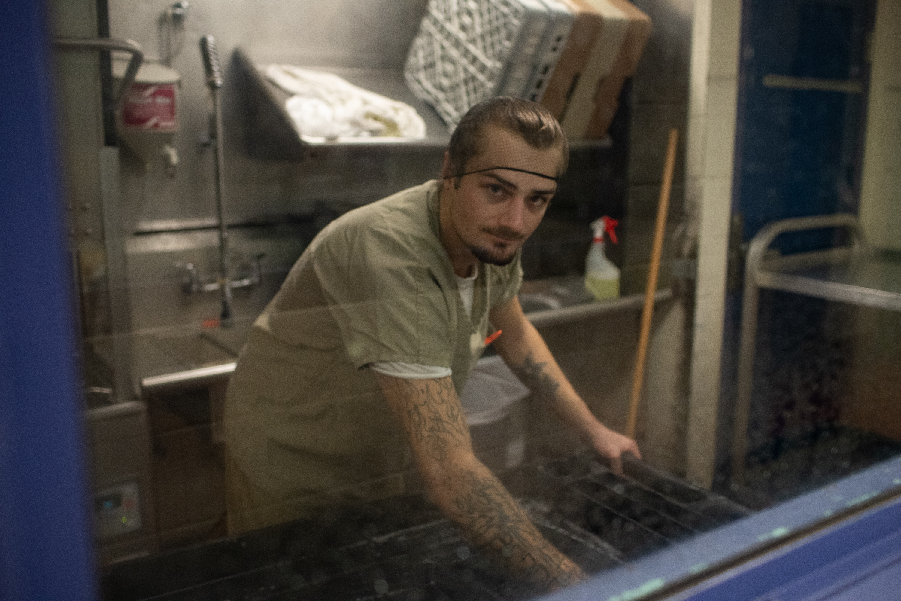 An inmate sanitizes a food cart in the jail kitchen. A moldy substance is visible on the walls and ceiling.
