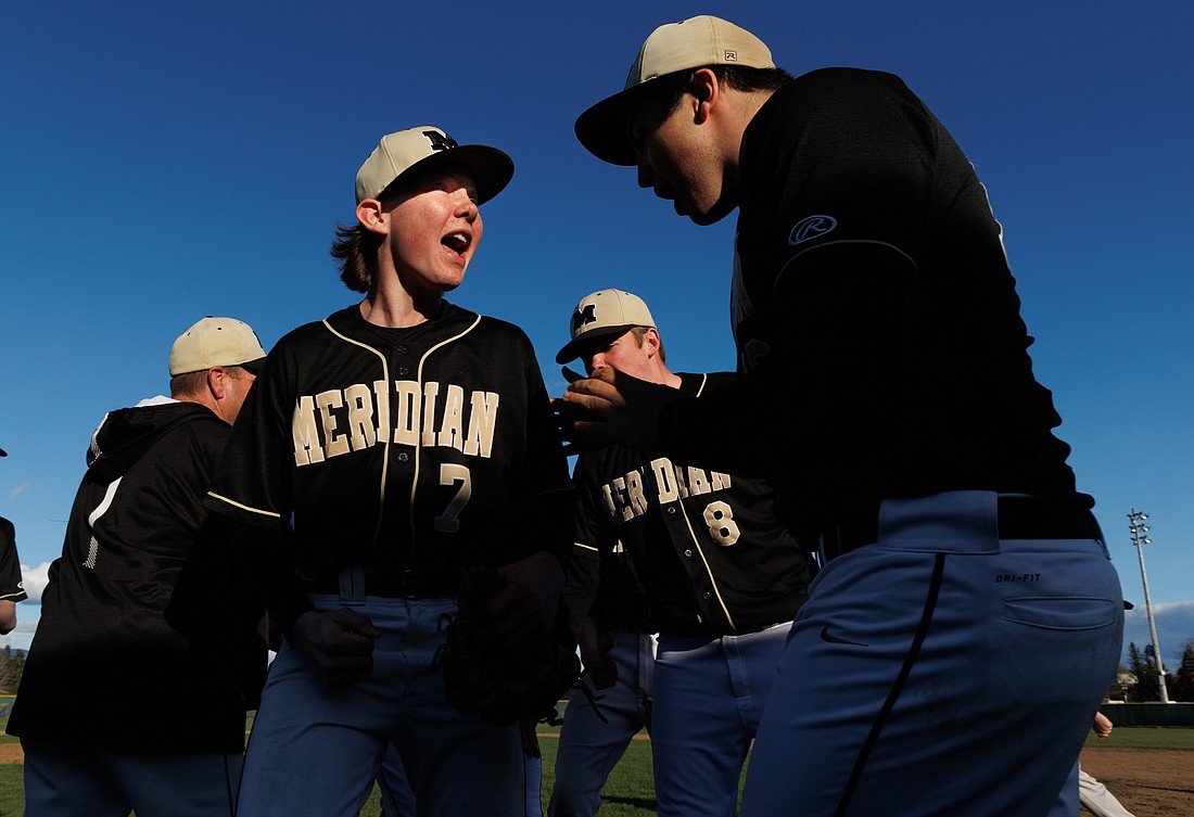 Meridian pitcher Jonah Aase (7) celebrates with teammates March 31, 2022, after a 4-3 win over Lynden.