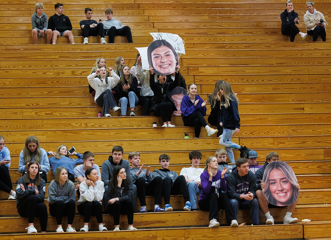 Meridian fans hold up a photo of Avery Neal, as she takes a shot, while Nooksack Valley’s fans hold one of Nooksack Valley’s Taylor Lentz.