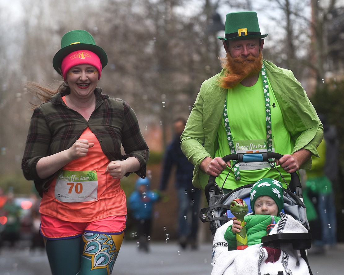 Dressed as leprechauns, Jessica Crocket and Cole Crocket cross the finish line with their child March 11 during the Runnin' O' the Green, a St. Patrick's Day-themed 5K and 8K race.