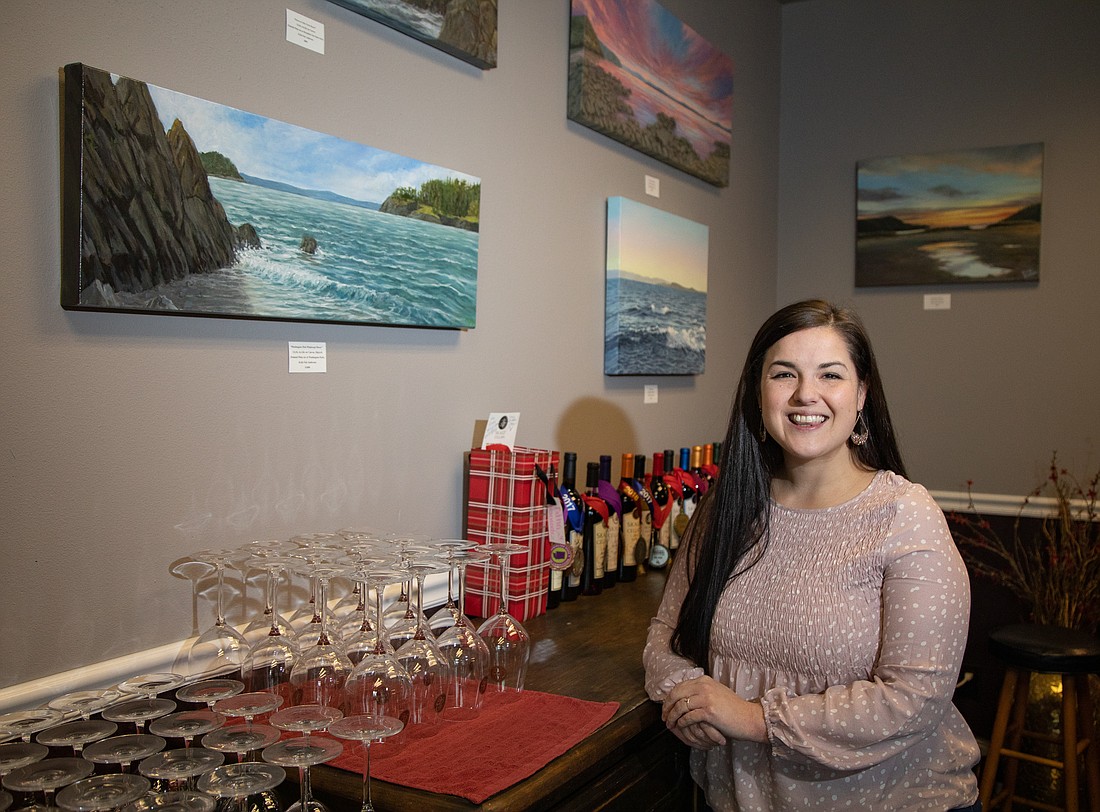 Kylie Fair Anderson stands with a collection of her paintings hanging at Skagit Cellars.